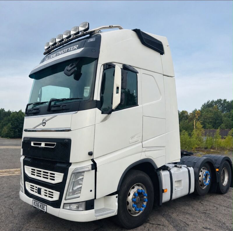 A white Volvo FH Globetrotter tractor unit with a roof light bar